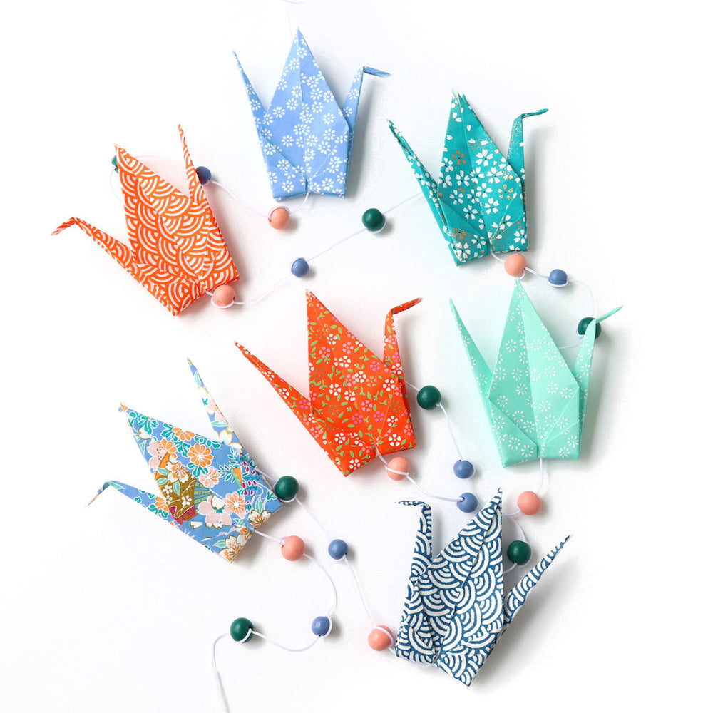 photo packshot de la guirlande montée du kit créatif guirlande de grues en origami « louisiane » (T8) dans les tons bleu pervenche et canard, orange et vert d'eau adeline klam