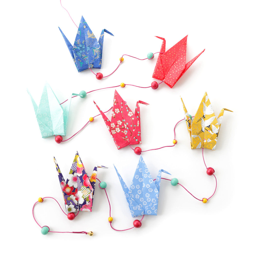 photo packshot de la guirlande montée du kit créatif guirlande de grues en origami « arc en ciel » (Y5) dans les tons bleu nuit et ciel, rouges, roses, vert d'eau et jaunes adeline klam