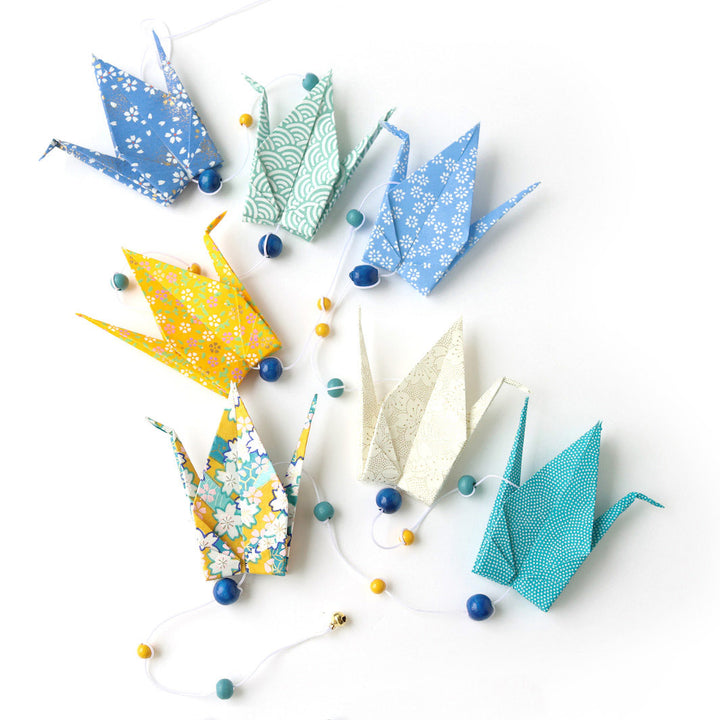 photo packshot de la guirlande montée du kit créatif guirlande de grues en origami « vahiné » (U6) dans les tons jaune moutarde, bleu pervanche et canard et vert d'eau adeline klam