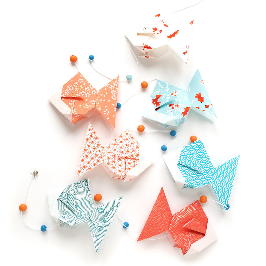 photo packshot de la guirlande montée du kit guirlande de poissons en origami dans les tons bleu ciel, turquoise, corail, rouges et oranges de la gamme « sunset » adeline klam