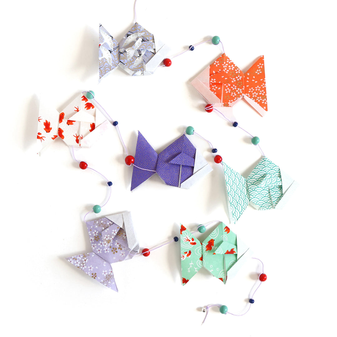 photo packshot de la guirlande montée du kit guirlande de poissons dans les tons vert d'eau, rouge orange, blanc crème et violet mauve « fluorite » adeline klam