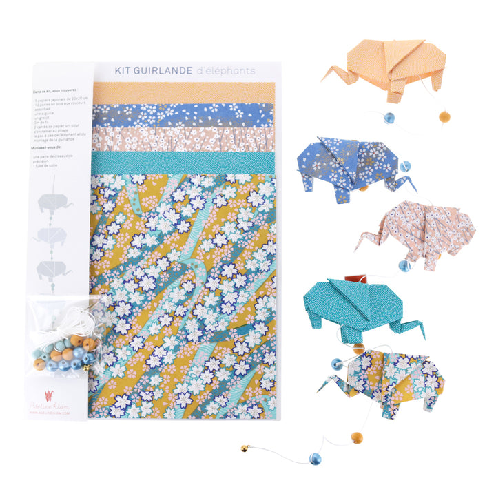 photo packshot du kit guirlande d'éléphants en origami, de la guirlande montée et du matériel dans les tons jaune safran, bleu pervenche, rose clair et bleu canard de la gamme « bombay » adeline klam