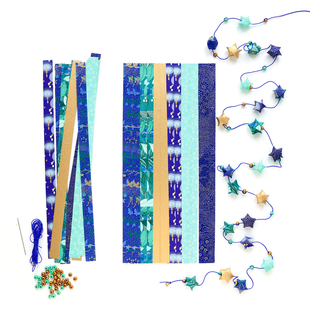 photo packshot de la guirlande montée et du matériel du kit guirlande d'étoiles en origami bleu nuit, bleu turquoise, vert, vert d'eau et doré « libellule » adeline klam