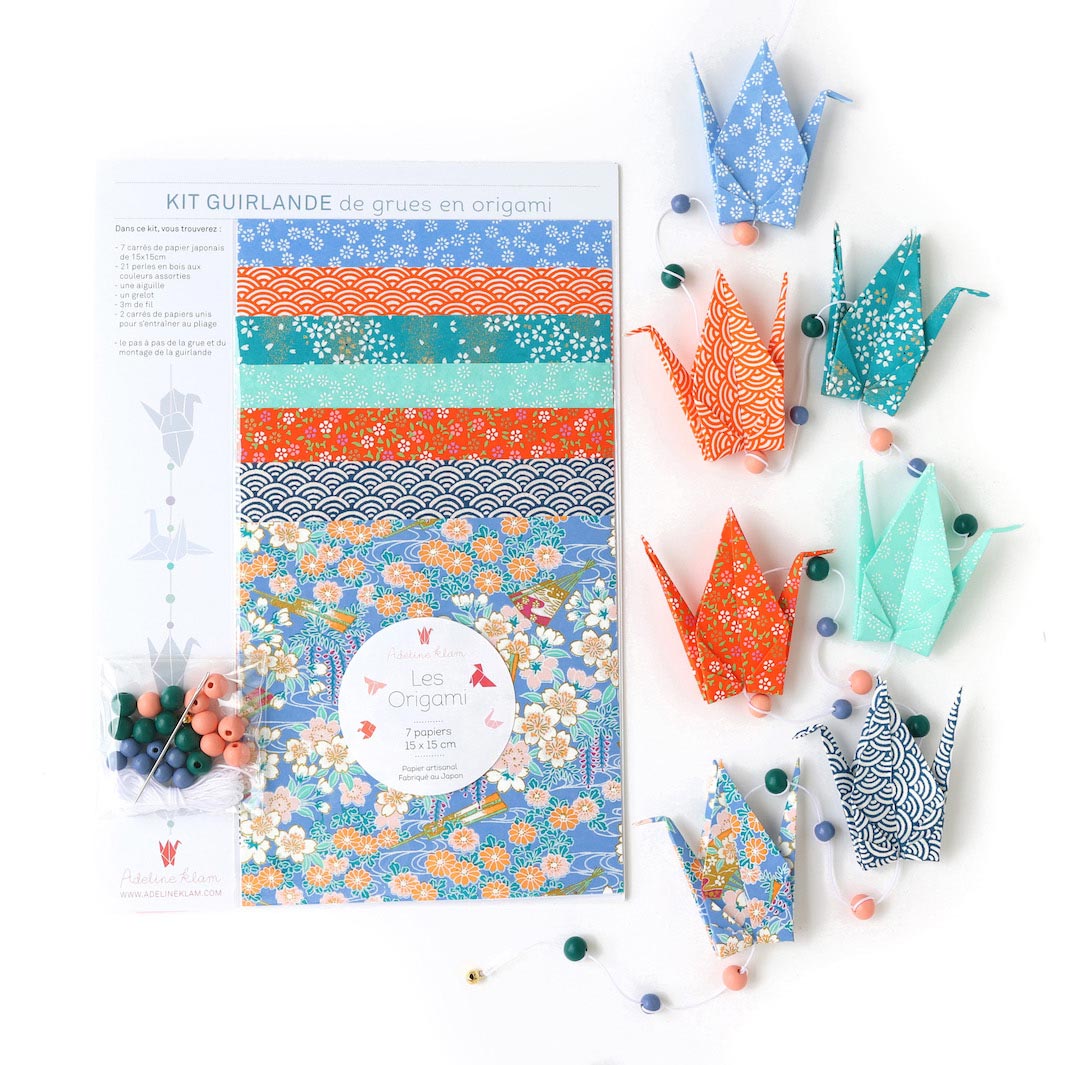 photo packshot de la guirlande montée et du packaging du kit créatif guirlande de grues en origami « louisiane » (T8) dans les tons bleu pervenche et canard, orange et vert d'eau adeline klam