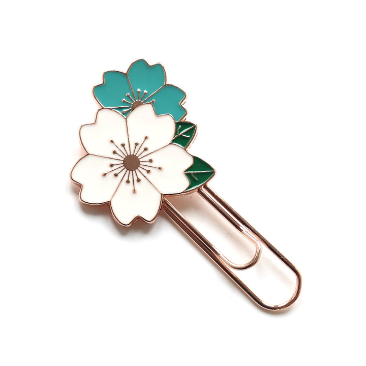 photo packshot du marque-page trombone or rose décoré de fleurs de cerisier blanches et bleues aux feuillages verts