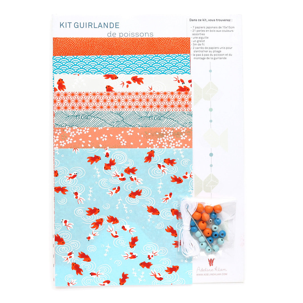 photo packshot du packaging du kit guirlande de poissons en origami dans les tons bleu ciel, turquoise, corail, rouges et oranges de la gamme « sunset » adeline klam