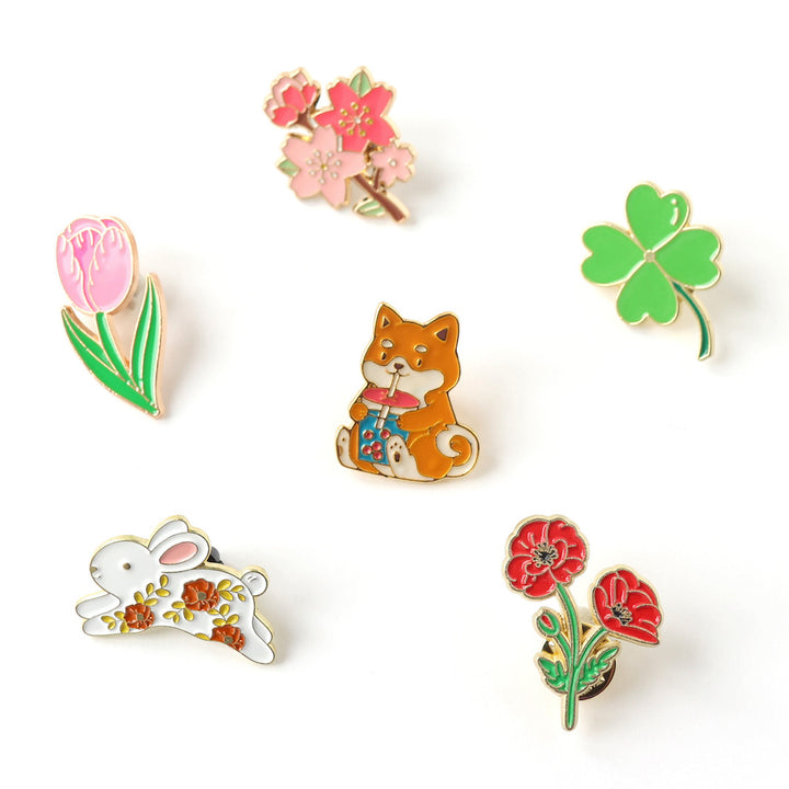 photo packshot de la sélection de pin's tulipe, branche de fleurs de cerisier, trèfle, lapin fleuri, chien shiba inu et bubble tea et coquelicot