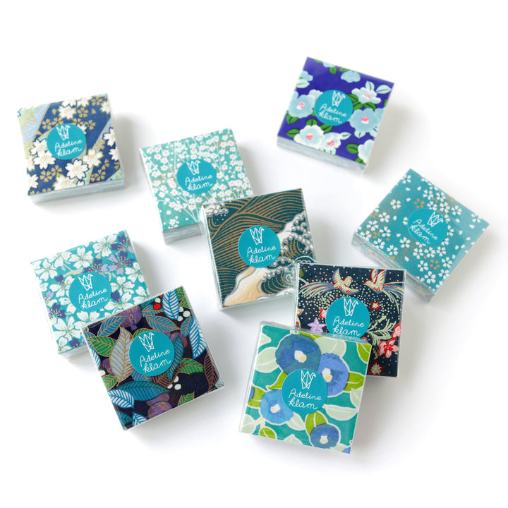 photo packshot de sets de 100 carrés de papiers japonais adeline klam de 6cm par 6cm dans les tons bleu canard, vert d'eau, bleu nuit, turquoise et violets « paon »