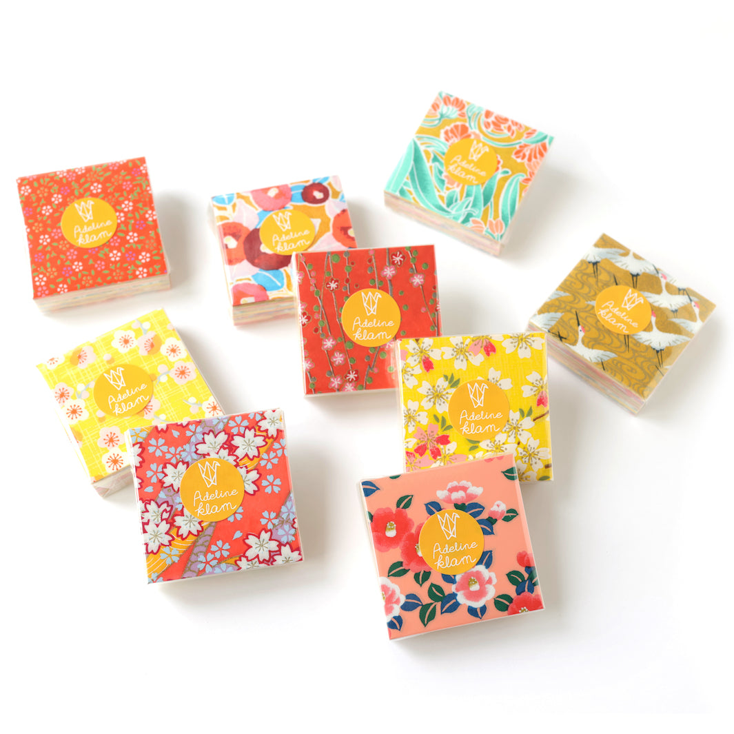 photo packshot de sets de 100 carrés de papiers japonais adeline klam de 6cm par 6cm dans les tons jaunes, orange, rouges, roses et bleu « multifruits »