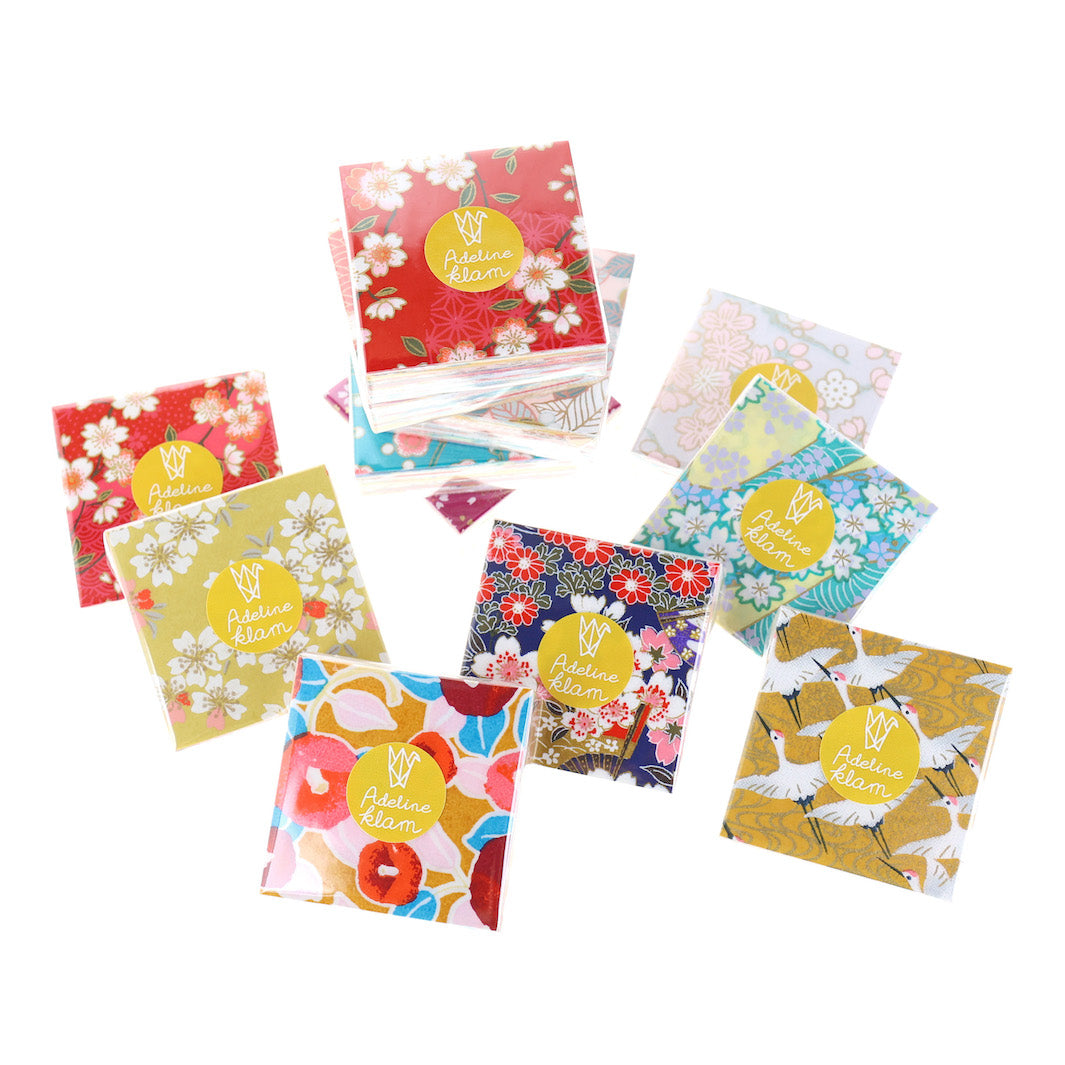 photo packshot de sets de 100 carrés de papiers japonais adeline klam de 6cm par 6cm dans les tons jaunes, orange, rouges, roses et bleu turquoise « multifruits »