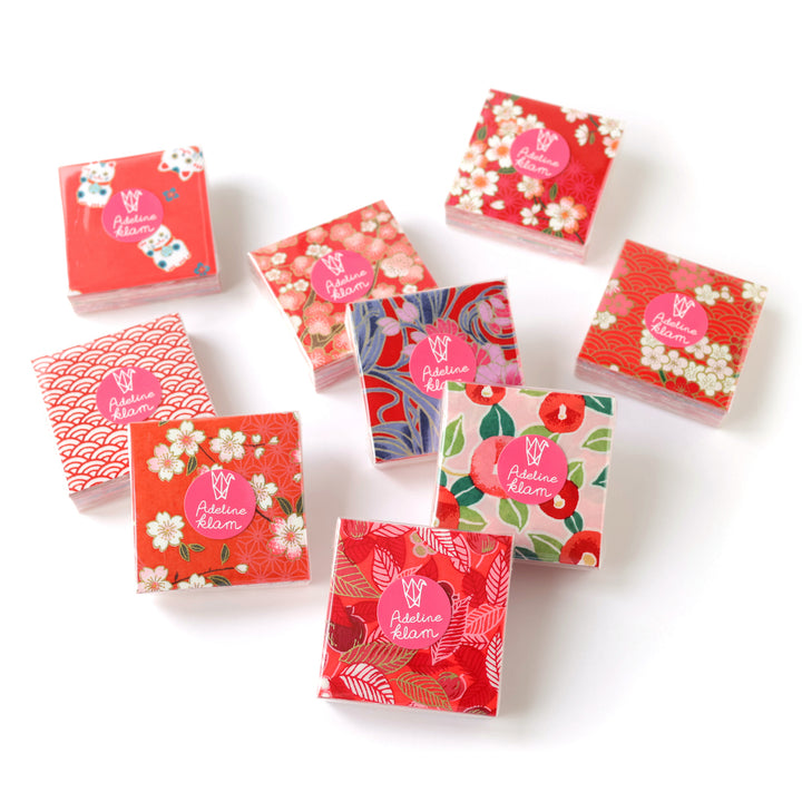 photo packshot de sets de 100 carrés de papiers japonais adeline klam de 6cm par 6cm dans les tons rouges, rouge orangé, corail, roses « grenadine »