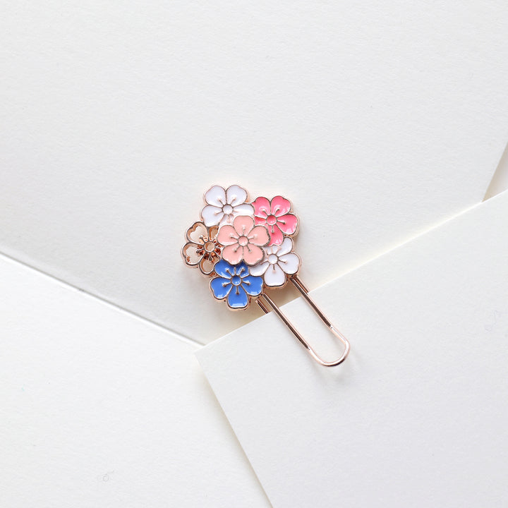 photo packshot de l'utilisation du marque-page trombone or rose décoré d'une grappe de fleurs de cerisier roses, blanches et bleues
