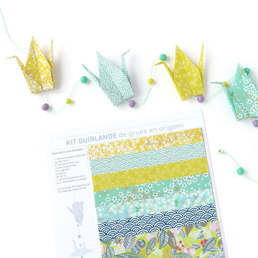 photo packshot zoomée de la guirlande montée et du packaging du kit créatif guirlande de grues en origami « lime » (K6) dans les tons jaune acidulé, vert d'eau et bleu foncé adeline klam