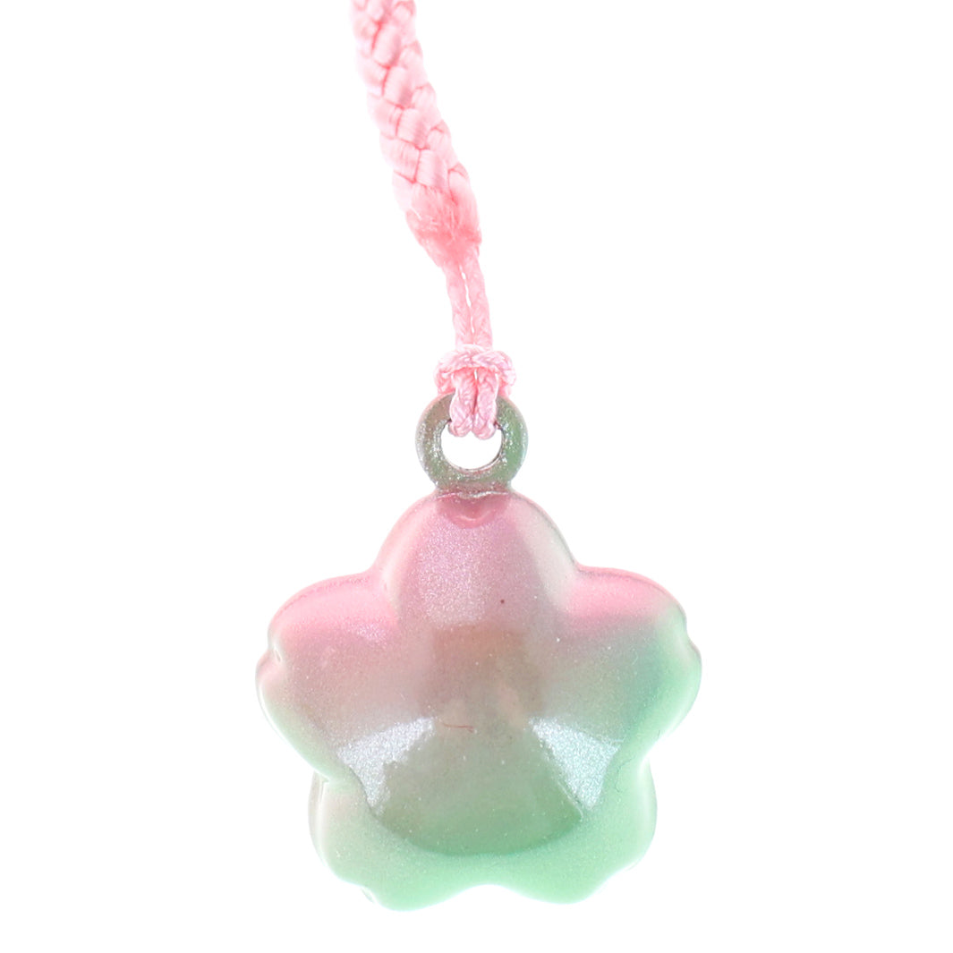 photo packshot zoomée d'un porte-clefs en forme de fleurs de cerisier de couleur vert et rose nacré