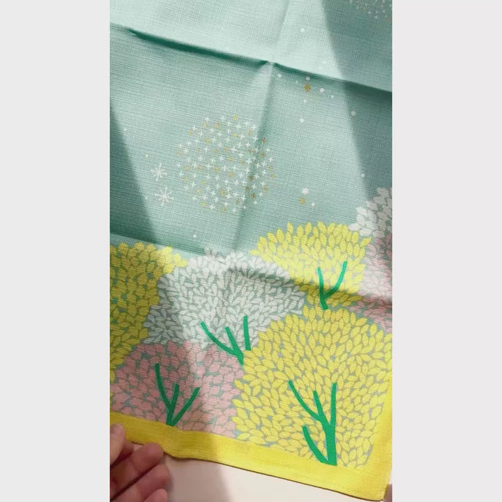 vidéo de démonstration du furoshiki au motif de forêt étoilée dans les tons jaune acidulé, vert de gris et roses adeline x musubi en 70cm par 70cm