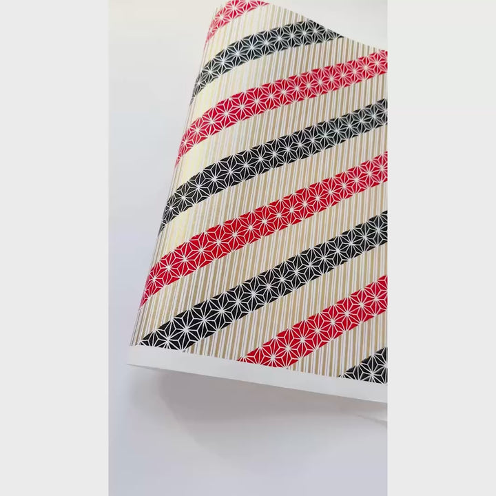vidéo de démonstration du papier japonais yuzen chiyogami aux motifs de lignes épaisses et de grandes étoiles dans les tons noirs, rouges et doré clair adeline klam (M1027)