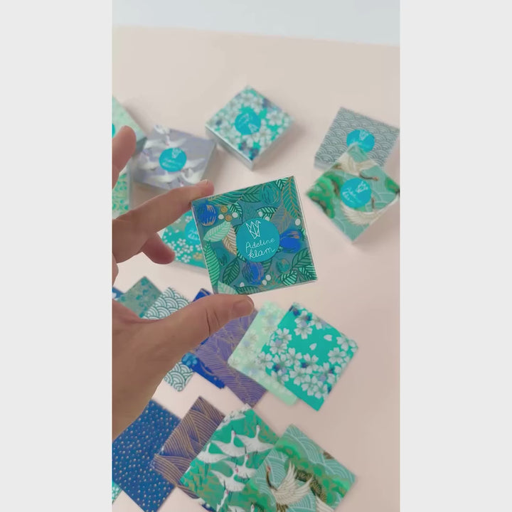 vidéo de démonstration de sets de 100 carrés de papiers japonais adeline klam de 6cm par 6cm dans les tons bleu canard, vert d'eau, bleu nuit, turquoise et violets « paon »