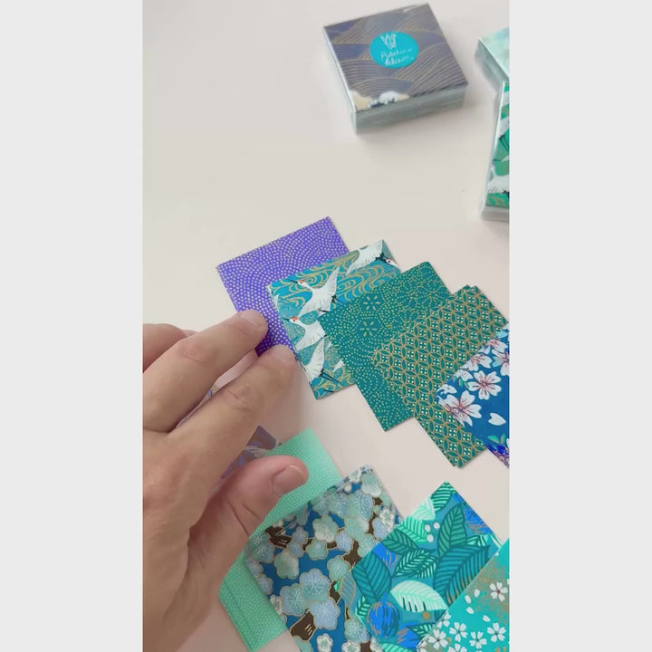vidéo de démonstration de sets de 100 carrés de papiers japonais adeline klam de 6cm par 6cm dans les tons bleu canard, vert d'eau, bleu nuit, turquoise et violets « paon »