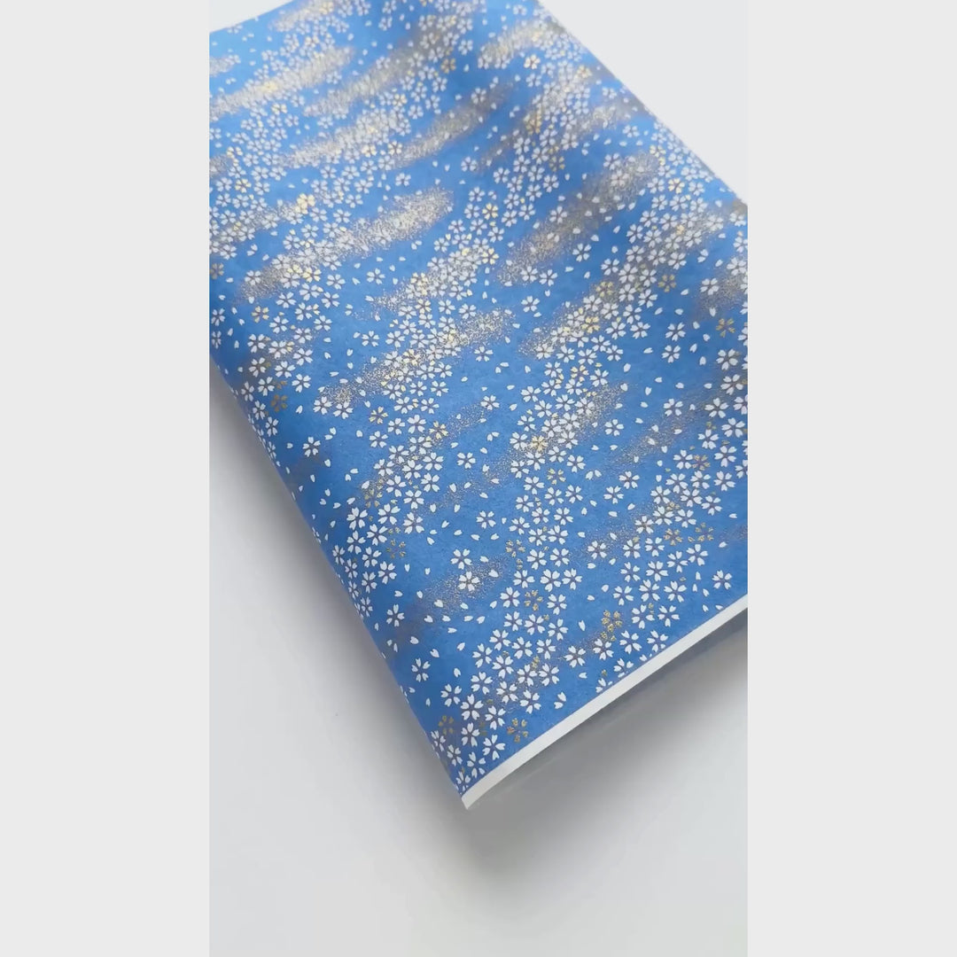 vidéo de démonstration du papier japonais yuzen chiyogami au motif de petits fleurs blanches au vent sur fond bleu pervenche adeline klam (M983)