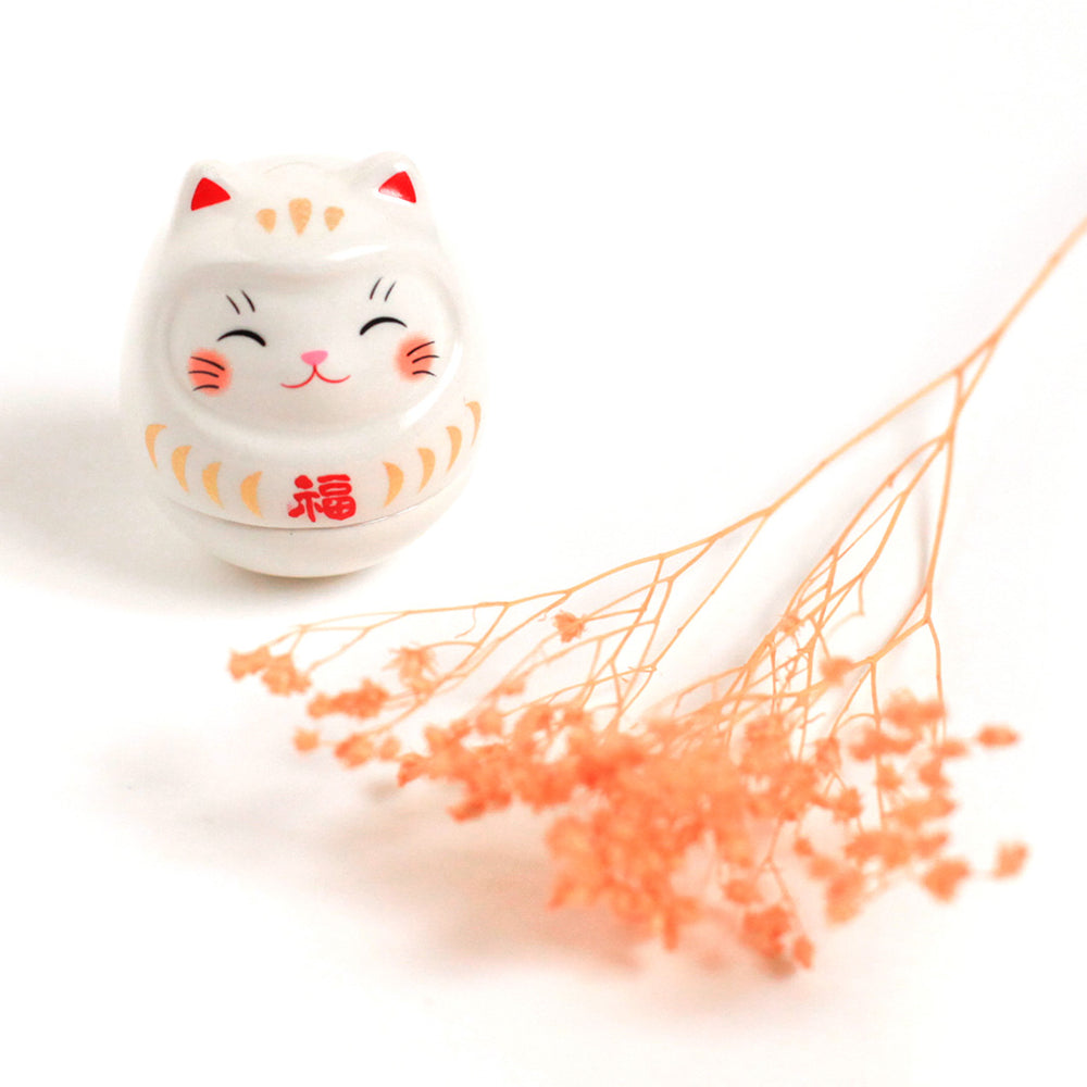 petit culbuto japonais ou koro-rin en forme de daruma chat blanc de face et fleurs séchées orange