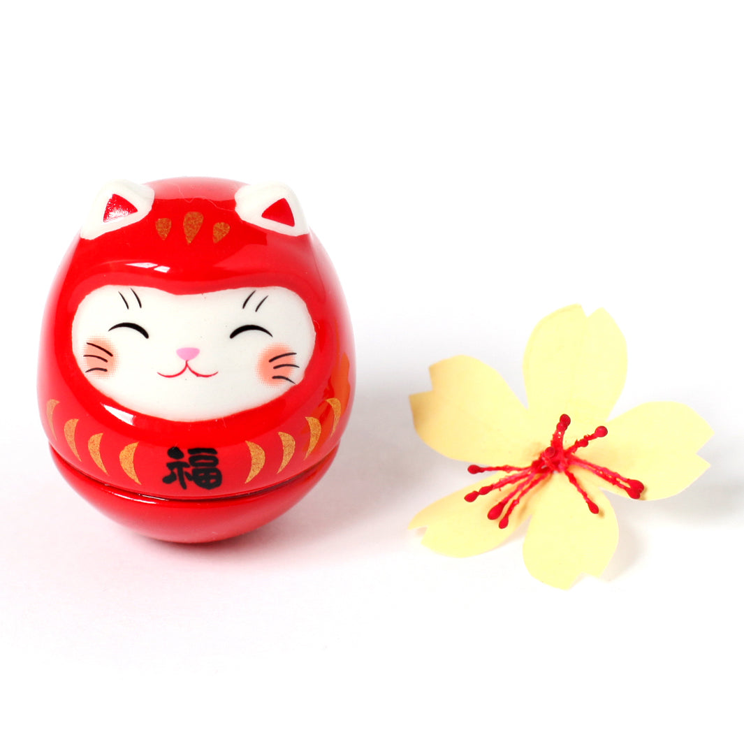 petit culbuto japonais ou koro-rin en forme de daruma chat rouge et petite fleur de cerisier jaune en origami