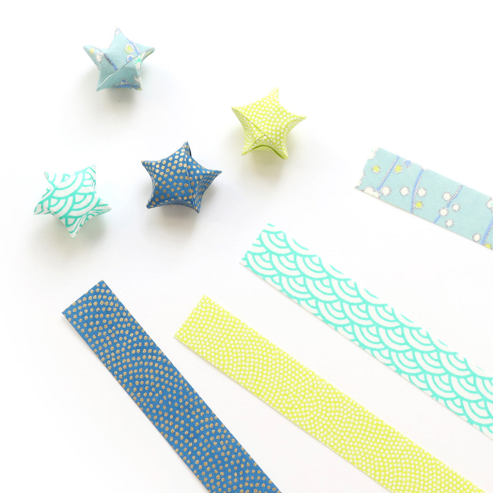 kit d'étoiles en origami et papier japonais bleu, turquoise et jaune acidulé « myosotis » adeline klam posé à plat en biais