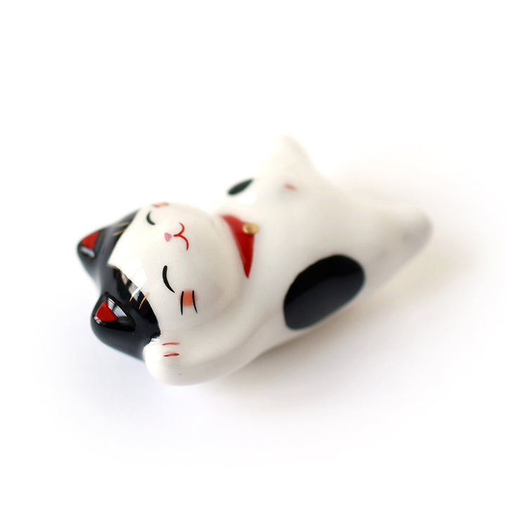 photo packshot d'un chat maneki-neko en céramique au pelage blanc moucheté de noir